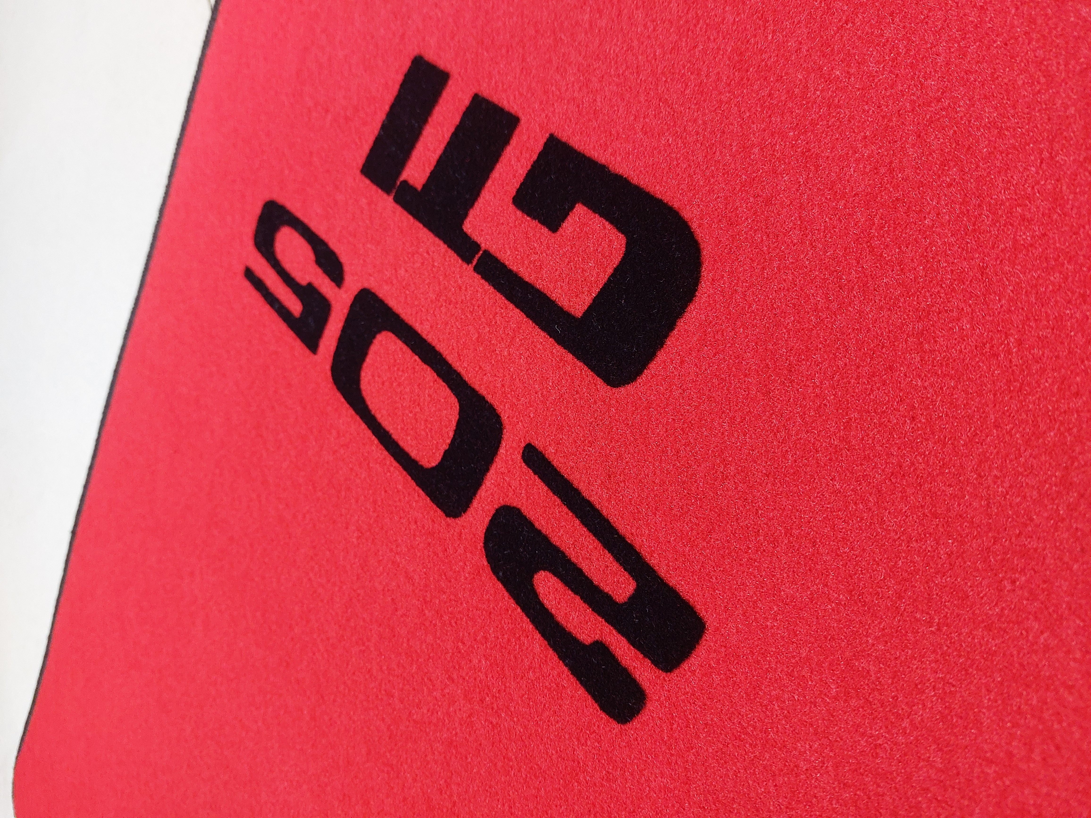 Seitliche ansicht des Peugeot 205 Gti Logos auf rotem Velours und Druck in schwarz.1 