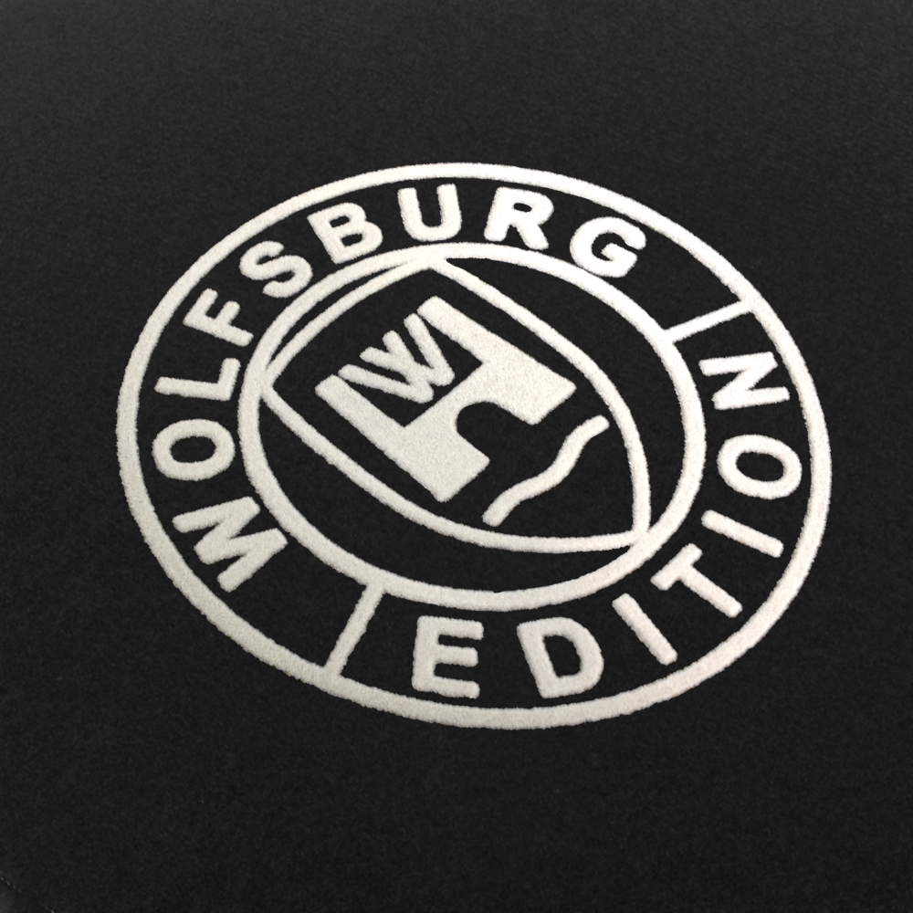 Das Wolfsburg Editions Logo auf einem schwarzen Teppich und das Logo ist in weiss.
